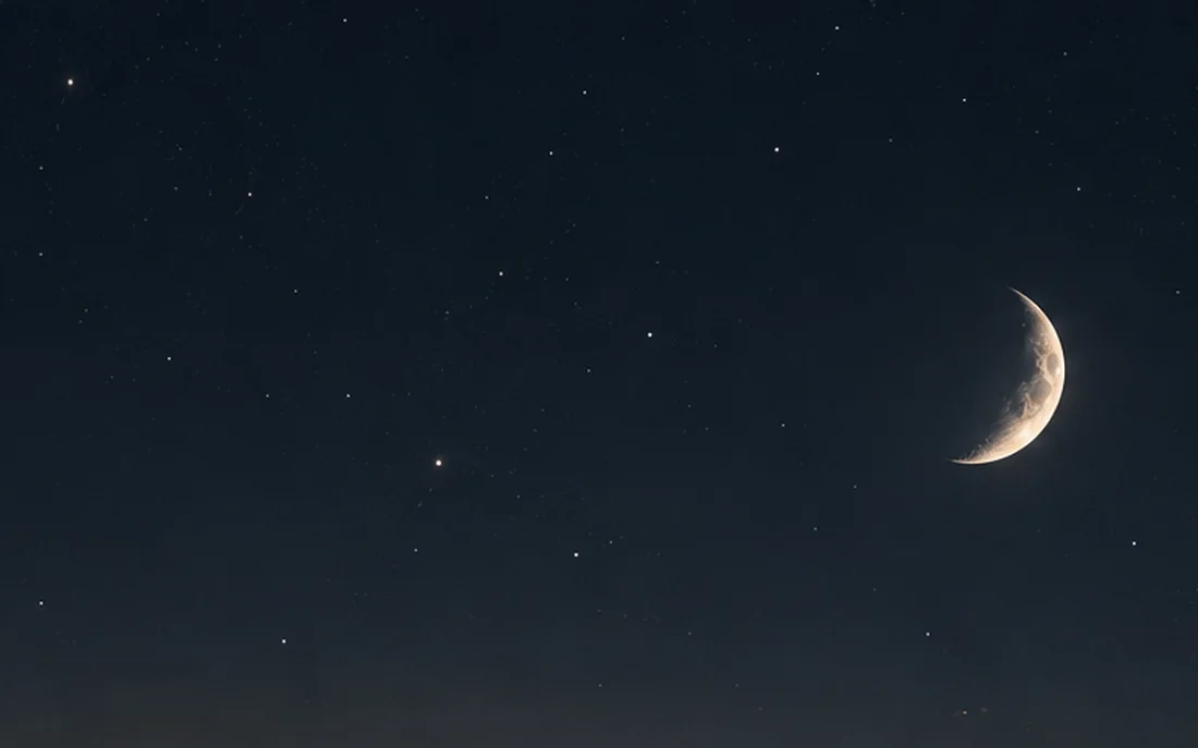 A crescent moon and stars over a darkening sky